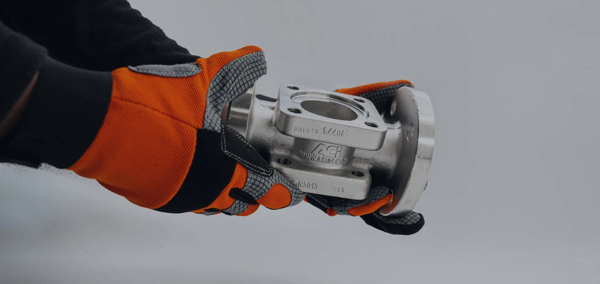 Jemand hält mit Handschuhen eine maßgeschneiderte Armatur von ACI in der Hand